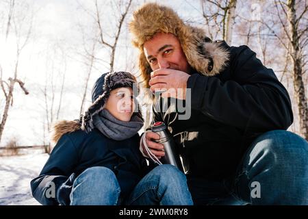 Vater trinkt Tee im Winter neben dem Sohn Stockfoto