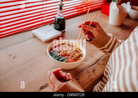 Frau isst Ramen-Nudeln mit Essstäbchen im Restaurant Stockfoto