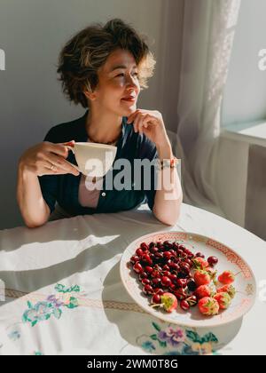 Reife Frau, die zu Hause Tee und Beeren trinkt Stockfoto