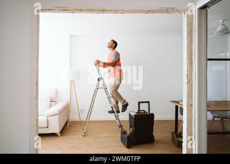 Techniker klettern auf Leiter im Haus, das gerade renoviert wird Stockfoto