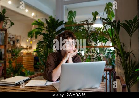 Aufmerksamer Besitzer eines Pflanzengeschäfts mit Laptop am Tisch im Laden Stockfoto