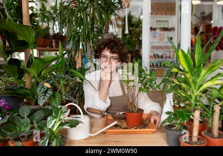 Lächelnde Botaniker-Töpferanlage am Tisch im Geschäft Stockfoto