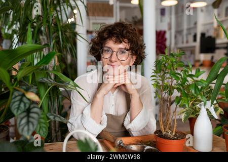 Lächelnder Botaniker, der sich auf Ellbogen in der Werkshalle stützt Stockfoto