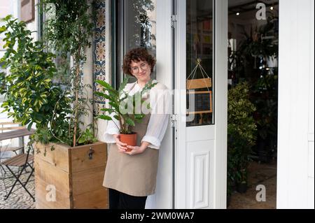 Ein lächelnder Besitzer hält am Eingang des Kindergartens eine Topfpflanze Stockfoto