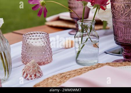 Picknick-Ästhetik, Tischdekoration, Blumenarrangements, Muscheln aus nächster Nähe. Gemütliche Einrichtung mit Blumen und Kerzen. Stockfoto