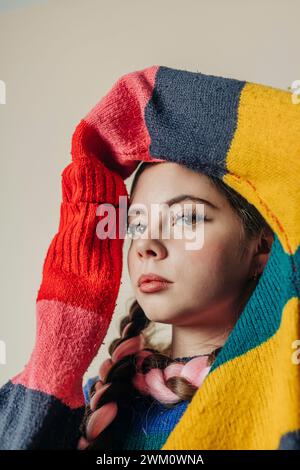 Frau mit mehrfarbigem Pullover in der Nähe der Wand Stockfoto