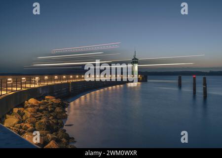 Deutschland, Schleswig-Holstein, Lübeck, verschwommene Bewegung des Schiffes am Leuchtturm von Travemunde bei Sonnenaufgang Stockfoto