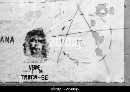 TOMAR, PORTUGAL - 28. APRIL 2015: Graffiti von Che Guevara auf der alten Hauswand, Text in Portugiesisch „zum Verkauf, zum Austausch“ und Anarchie-Symbol. Schwarzweiß Stockfoto