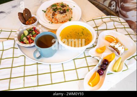 Usbekische Nationalgerichte, Plov, Shurpa, Salat und nicht auf einem Tablett mit Tee. Traditionelle usbekische Küche. Hintergrund mit kariertem Tischtuch. Stockfoto