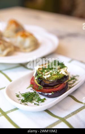 Auswahl an gegrilltem Gemüse (Tomaten, Auberginen, Zucchini) mit Kräutern und Gewürzen auf weißem Hintergrund. Stockfoto