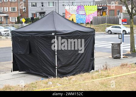 Washington, DC, USA. Februar 2024. (NEU) Polizeibeamte am Tatort einer Schießerei im Block 300 der 63rd Street, NE, bei der eine Person verletzt und eine Person getötet wurde. 23. Februar 2024, Washington, DC, USA: Mehrere Beweismarker durchsuchten das Gebiet, in dem sich Granathüllen am Tatort befanden, und am Tatort konnte auch ein Zelt gesehen werden, das die Person bedeckte, die am Tatort für tot erklärt wurde. Ein Willkommen in Washington, DC-Schild mit Graffiti „F*** Biden“ ist mit der Aufnahmeszene in der Ferne zu sehen. Die Schießerei fand um etwa 5:30 UHR AM Freitagmorgen statt Stockfoto