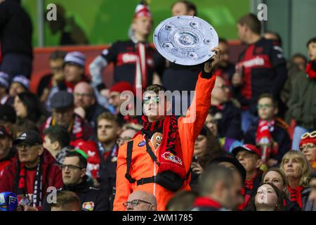 Leverkusen, Deutschland. Februar 2024. firo: 10.02.2024, Fußball, 1. Bundesliga, 1. Liga, Saison 2023/2024, Bayer 04 Leverkusen - FC Bayern München Fan Leverkusen mit Meisterschaftstrophäe Credit: dpa/Alamy Live News Stockfoto