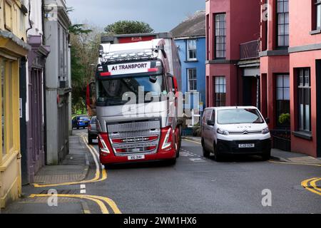 LKW fahren auf der Rhosmaen Street vorbei an geparkten Autos vor den Geschäften die Hauptstraße durch die Stadt Llandeilo Carmarthenshire Wales UK 2024 Stockfoto