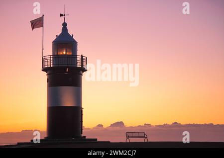 Leuchtturm und Bank bei Sonnenuntergang Stockfoto