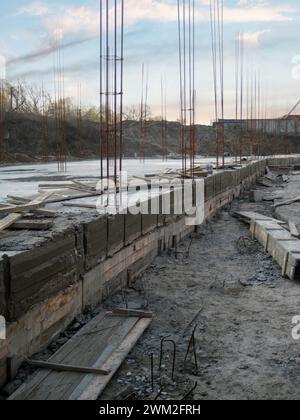 Frühstadium der Betonplatten- und Bewehrungskonstruktion. Bewehrungsrahmen auf schlammiger Baustelle Stockfoto