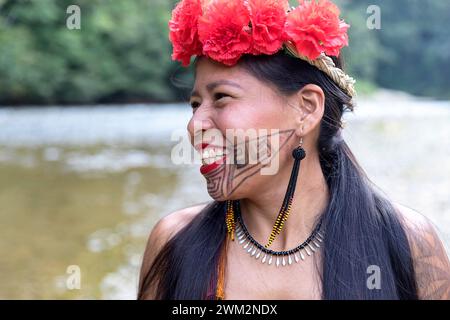 Eine lächelnde, schöne Frau aus dem Stamm der Embera aus einem Dorf im Chagres-Nationalpark mit traditionellen Tattoos im Gesicht und Blumen im Haar, Panama Stockfoto