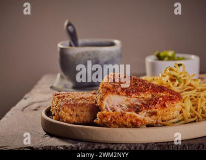 Panierte Thunfischsteaks mit Estragonnudeln. Stockfoto