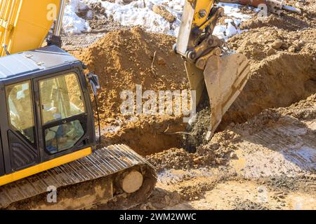 Der Graben wird von einem Bagger im Rahmen der Erdbewegung auf der Baustelle ausgehoben, um den Infrastrukturbereich vorzubereiten Stockfoto