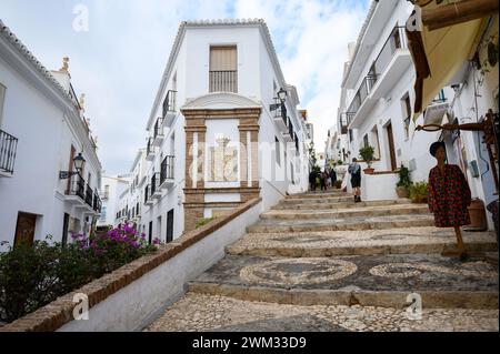 Bergab und steile Straßen bergauf, wo Menschen in einem der schönsten Dörfer Spaniens, Frigiliana, Malaga, Spanien, spazieren gehen. Stockfoto