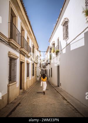 Eine wunderschöne junge Frau, elegant gekleidet, spaziert durch das Viertel San Basilio in der historischen Altstadt von Cordoba, Andalusien, Spanien, im Sommer Stockfoto