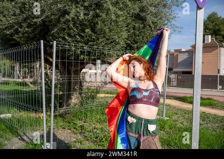 Eine junge Frau in einem Hemd hält einen farbenfrohen Regenbogenschal Stockfoto