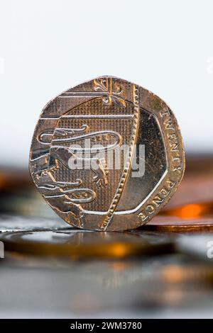 Studio-Aufnahme von einem 20 Pence in Sterling-Währung, das aufrecht auf dem Tisch steht, mit unscharfen Münzen im Vordergrund Stockfoto