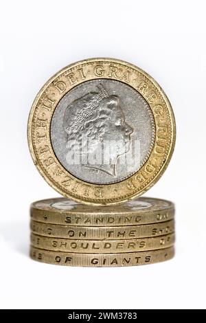 Studio-Aufnahme von zwei Pfund Sterling-Münzen im Stapel, die „auf den Schultern von Riesen stehen“ mit einer aufrechten zwei-Pfund-Münze, die auf dem oberen Agave ausbalanciert ist Stockfoto