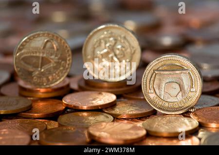 Studio-Aufnahme von drei-Pfund-Münzen in Sterling-Währung, die aufrecht auf dem Tisch stehen, mit unscharfen Münzen im Hintergrund Stockfoto