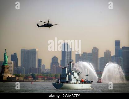 HMS Scott, Hubschrauber und Schlepper, die Wasser in der Nähe der Freiheitsstatue mit Ellis Island und Jersey City, New Jersey Skyline im Hintergrund, Stockfoto