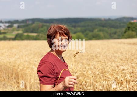 Porträt einer lächelnden Seniorin, die auf einem Weizenfeld steht. Stockfoto