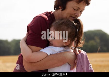 Großmutter und Enkelin umarmen sich im Weizenfeld. Glückliches Familienkonzept. Stockfoto