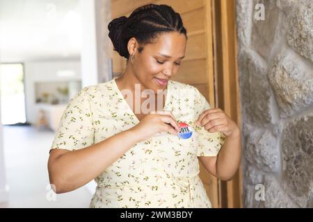 Eine junge Frau klebt zu Hause ein Stimmabzeichen auf ihr Hemd Stockfoto