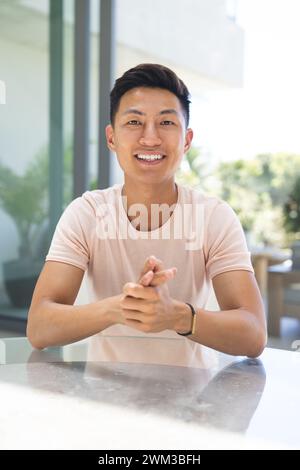 Ein junger asiatischer Mann lächelt bei einem Videoanruf hell in die Kamera Stockfoto