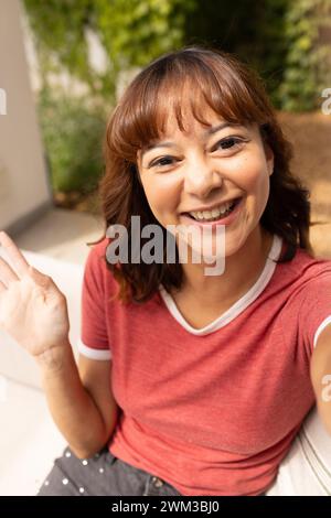 Junge birassische Frau winkt fröhlich bei Videogesprächen Stockfoto