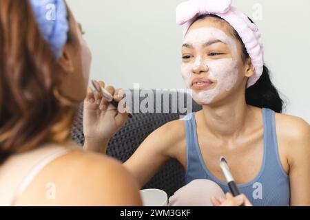 Zwei junge Frauen mit birassischer Herkunft machen zu Hause eine Hautpflegeroutine Stockfoto