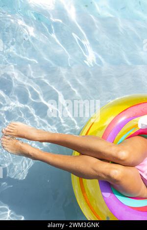 Die Person entspannt sich auf einem farbenfrohen Schwimmer in einem Pool, mit Platz zum Kopieren Stockfoto