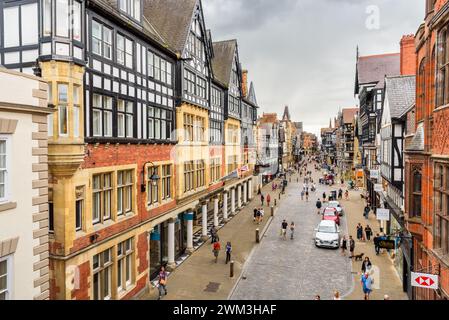 Chester, England - 9. Juli 2023: Menschen schlendern entlang der Eastgate Street unter Sturmhimmel. Eastgate ist die Haupteinkaufsstraße in Chester. Stockfoto