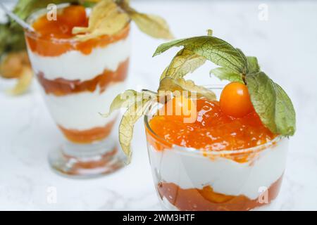 Nahaufnahme eines mehrschichtigen Desserts mit Proteinjoghurt und Physalis in einem Glas Stockfoto