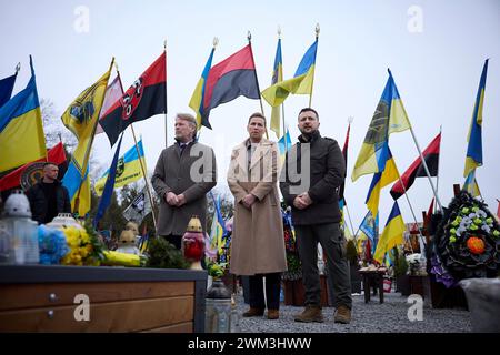 Lviv, Ukraine. Februar 2024. Der dänische Premierminister Mette Frederiksen, Mitte, der Ehemann Bo Tengberg, links und der ukrainische Präsident Wolodymyr Zelenskyj, rechts, stehen auf dem Marsfeld auf dem Lytschakiw-Friedhof am 23. Februar 2024 in Lemberg, Ukraine, für einen Moment der Stille. Quelle: Pool Photo/Ukrainische Präsidentenpresse/Alamy Live News Stockfoto