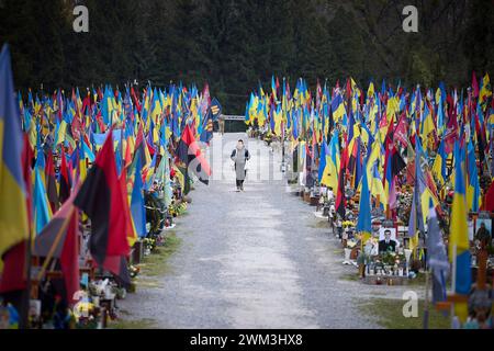 Lviv, Ukraine. Februar 2024. Eine Frau geht das Zentrum des Marsfeldes entlang, vorbei an Tausenden ukrainischer und militärischer Kampfflaggen auf dem Lytschakiv-Friedhof, 23. Februar 2024 in Lemberg, Ukraine. Quelle: Pool Photo/Ukrainische Präsidentenpresse/Alamy Live News Stockfoto