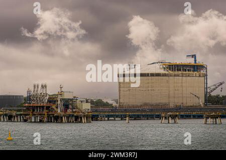 Limon Bay, Colon, Panama - 24. Juli 2023: AES Colon Kraftwerk oder Termoelectrica, Hauptgebäude und Entladepier für fossile Brennstoffe für Schiffe unter Grau Stockfoto