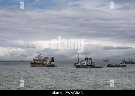 Limon Bay, Colon, Panama - 24. Juli 2023: Wartende Schiffe ankern in der Bucht vor dem Hafen unter blaugrauer, dichter Wolkenlandschaft Stockfoto