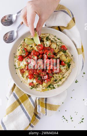 Gebratene Blumenkohltomaten und Hummus-Salat auf weißem Hintergrund topview Stockfoto