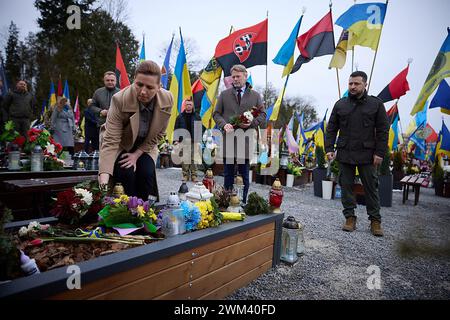 Lemberg, Lemberg, Ukraine. Februar 2024. Die dänische Premierministerin METTE FREDERIKSEN, links, legt Blumen auf das Grab eines gefallenen Soldaten, während ihr Ehemann BO TENGBERG, Zentrum, und der ukrainische Präsident WOLODYMYR ZELENSKYY, rechts, auf das Marsfeld im Lychakiv-Friedhof schauen. (Credit Image: © Ukraine Presidency/ZUMA Press Wire) NUR REDAKTIONELLE VERWENDUNG! Nicht für kommerzielle ZWECKE! Stockfoto