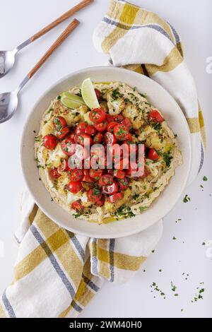 Gebratene Blumenkohltomaten und Hummus-Salat auf weißem Hintergrund topview Stockfoto