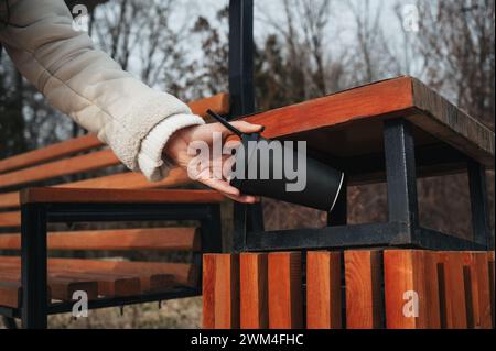 Frau Hand wirft einen recycelbaren Karton Kaffee in einen Mülleimer in einem Park Stockfoto