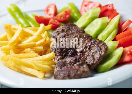 Traditionelle türkische Fleischbällchen serviert mit Pommes frites Tomaten Stockfoto
