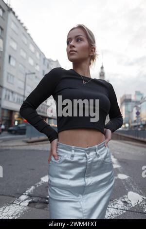 Stilvolles Urban Model Frau im modischen Outfit mit schwarzem Oberteil, das in der Stadt posiert Stockfoto