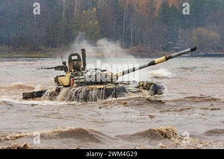 Ein mächtiger Tank für schwere Kampffahrzeuge verlässt das Flussufer, nachdem er eine Wasserbarriere entlang des Bodens gedrückt hat Stockfoto