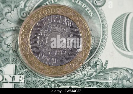 US-Dollar und zwei britische Pfund-Münze mit Königin Elizabeth II. Auf der Vorderseite und vier konzentrischen Kreisen für die Eisenzeit, Industrial Revo Stockfoto